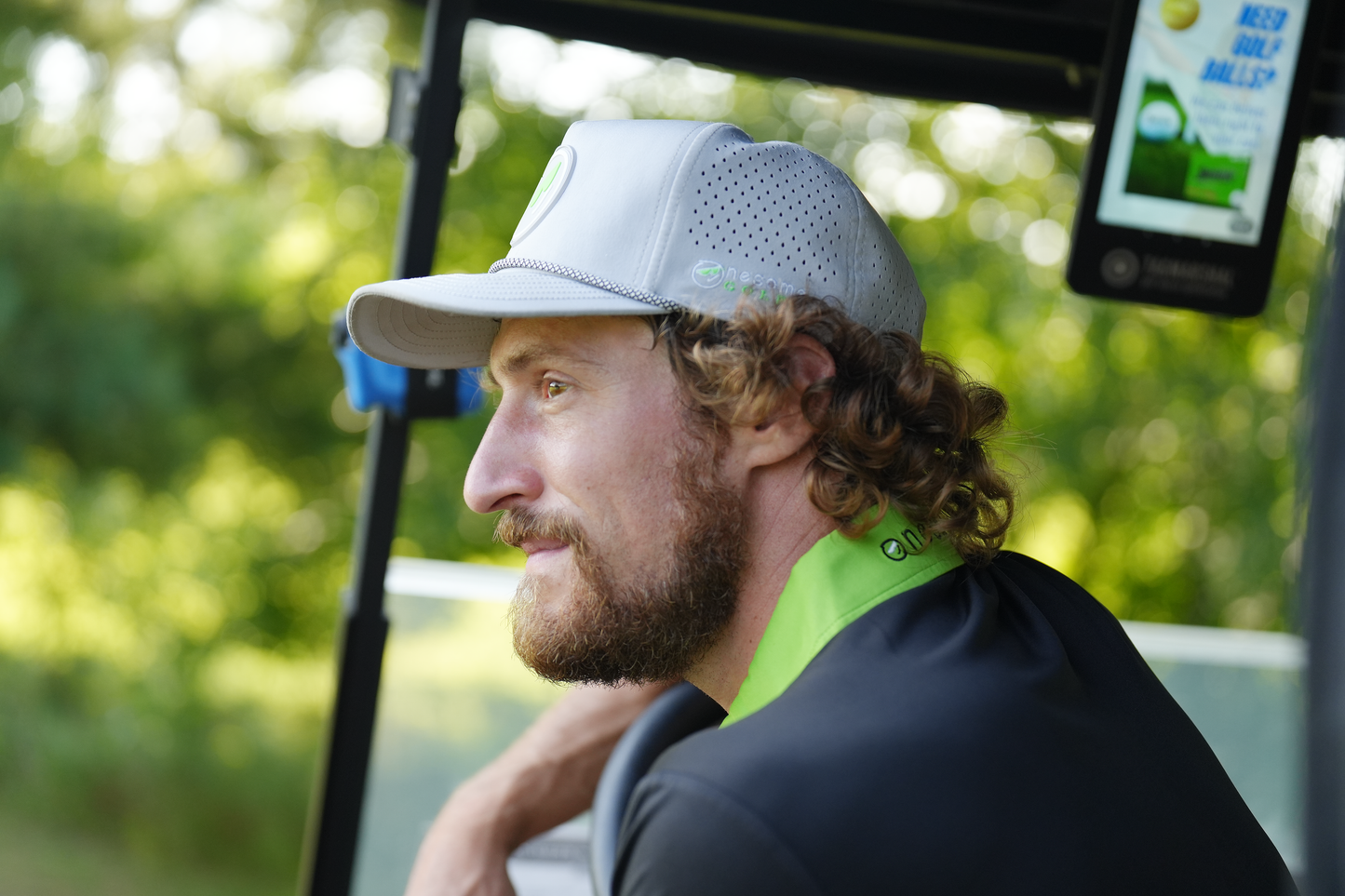 Man in golf cart wearing a gray Onesome hat