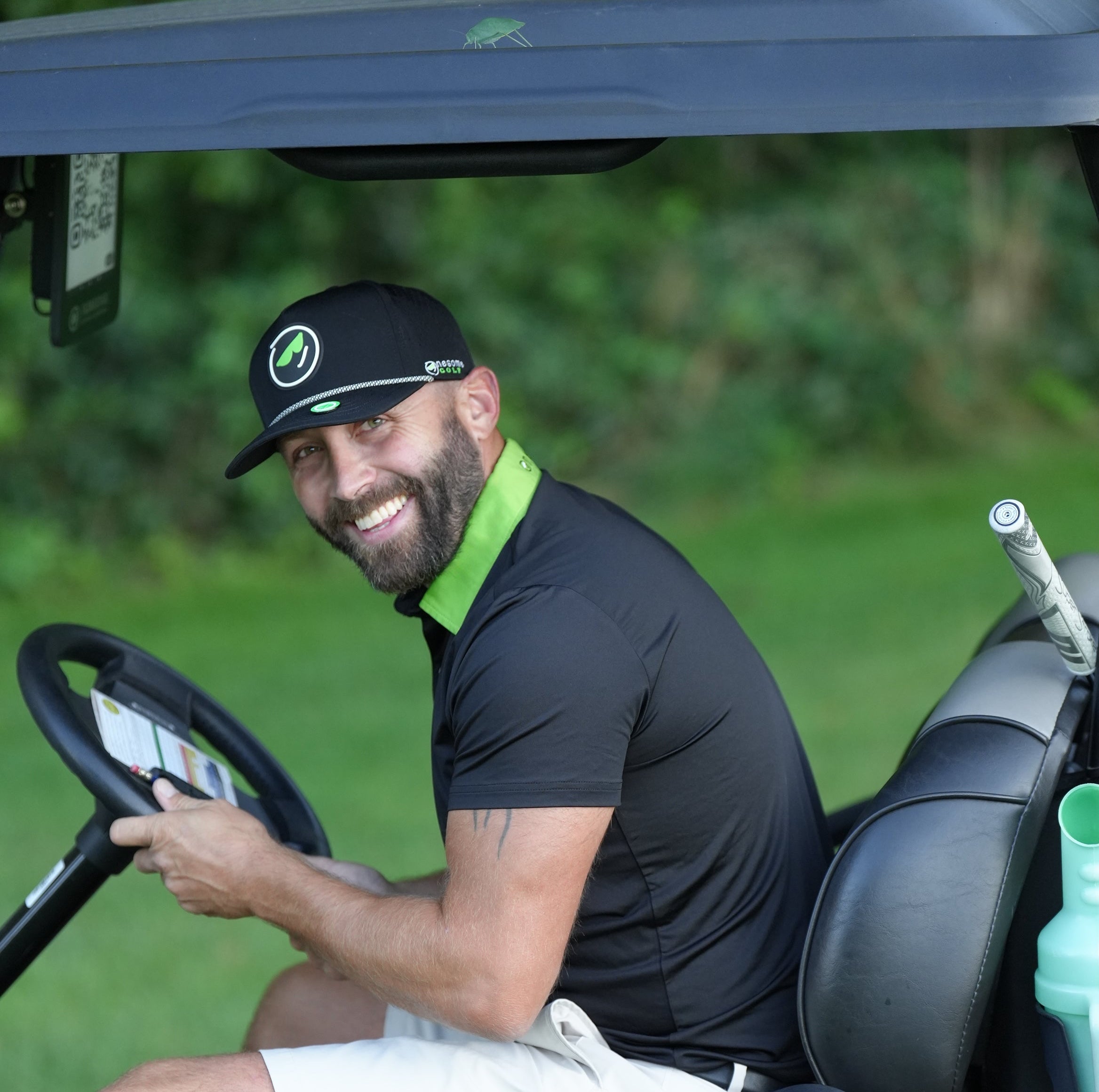Man sitting in a golf cart on a golf course wearing Onesome apparel