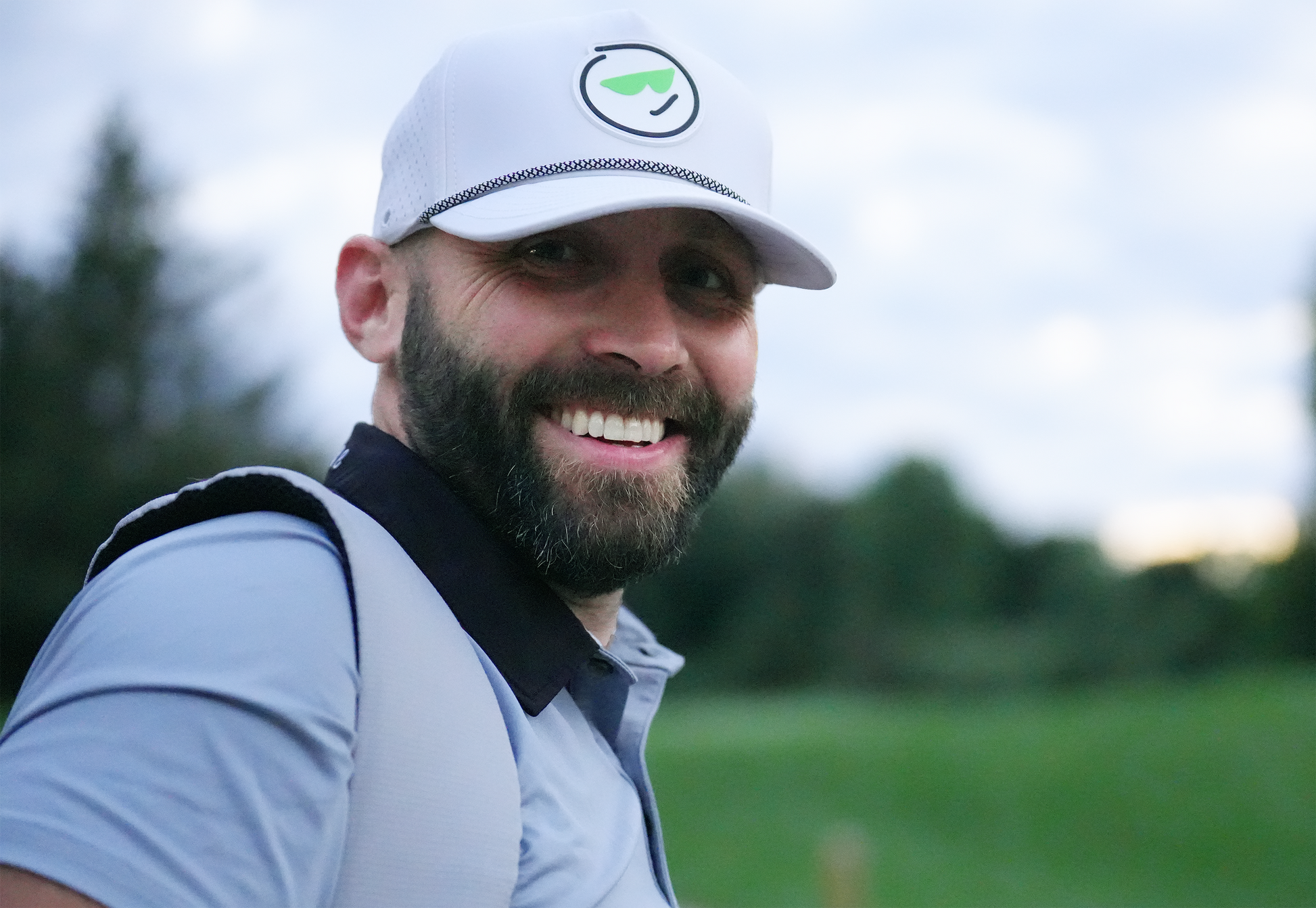 Man with golf bag on shoulder wearing a white golf hat